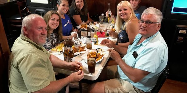 Group of seven people enjoying a meal together at a restaurant table.
