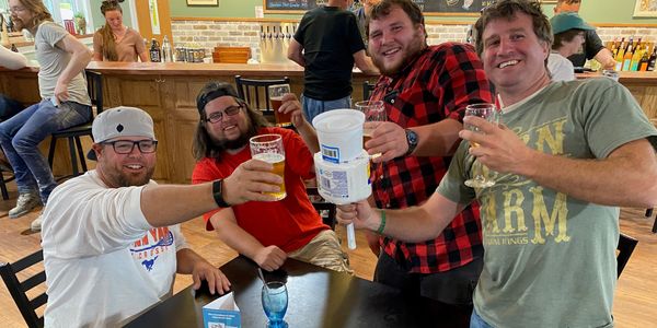 Four friends cheer with drinks in a lively bar setting.